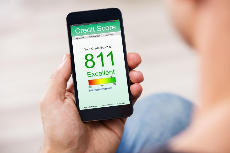 Person holding a cell phone with a screen showing a credit score of 811