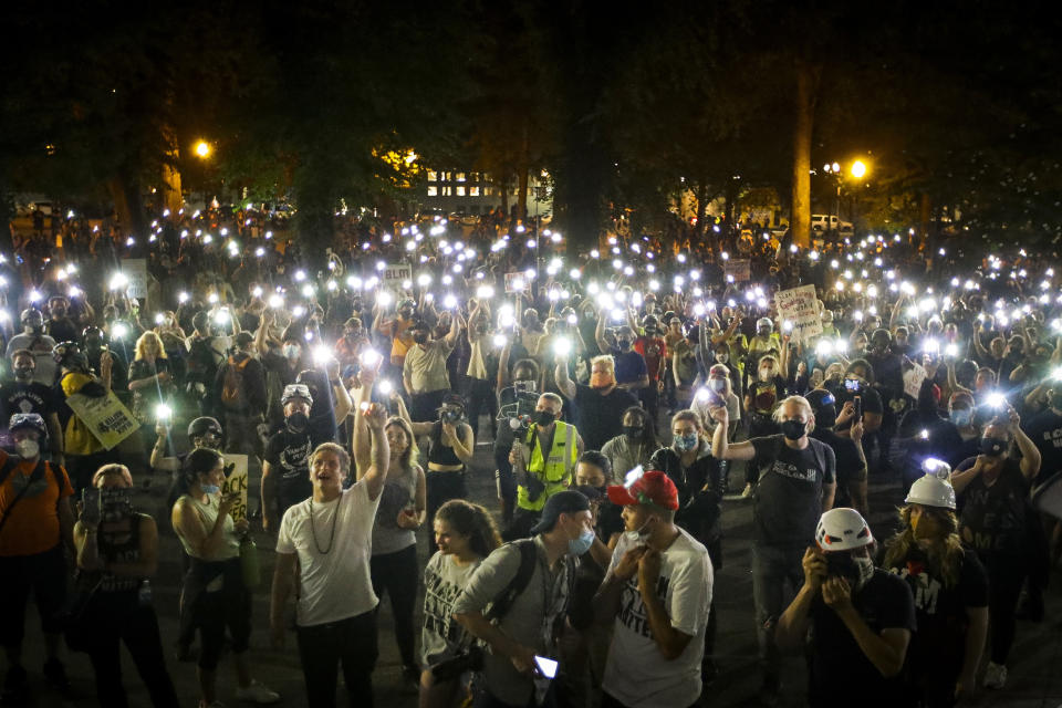 Demonstrators raise their cell phone lights as they chant slogans during a Black Lives Matter protest at the Mark O. Hatfield United States Courthouse Wednesday, July 29, 2020, in Portland, Ore. (AP Photo/Marcio Jose Sanchez)