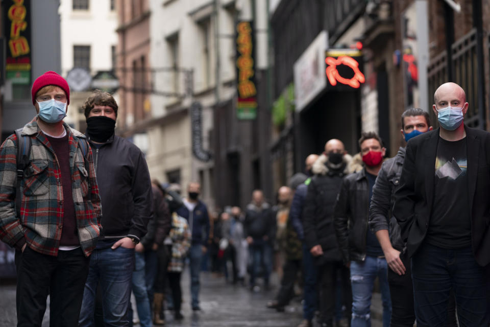 Members of the entertainment industry stand on Matthew Street in Liverpool, England, Monday Oct. 12, 2020, during a show of support for the hard hit sector as Prime Minister Boris Johnson lays out a new three-tier alert system for England. The British government is set to announce new restrictions on business and socializing in major northern England cities with high infection rates, under a plan to put areas into three tiers. (AP Photo/Jon Super)