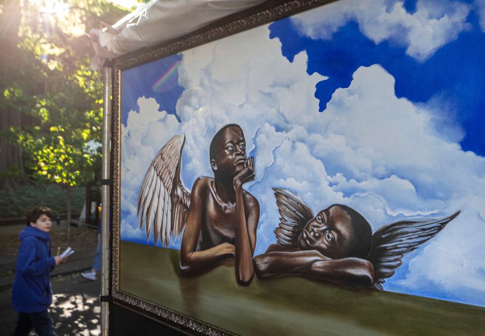Artist Daniel Johnson's painting, a take-off of Raphael's "the Cherubs," hangs outside his booth a the St. James Court Art Show. Sept. 30, 2022