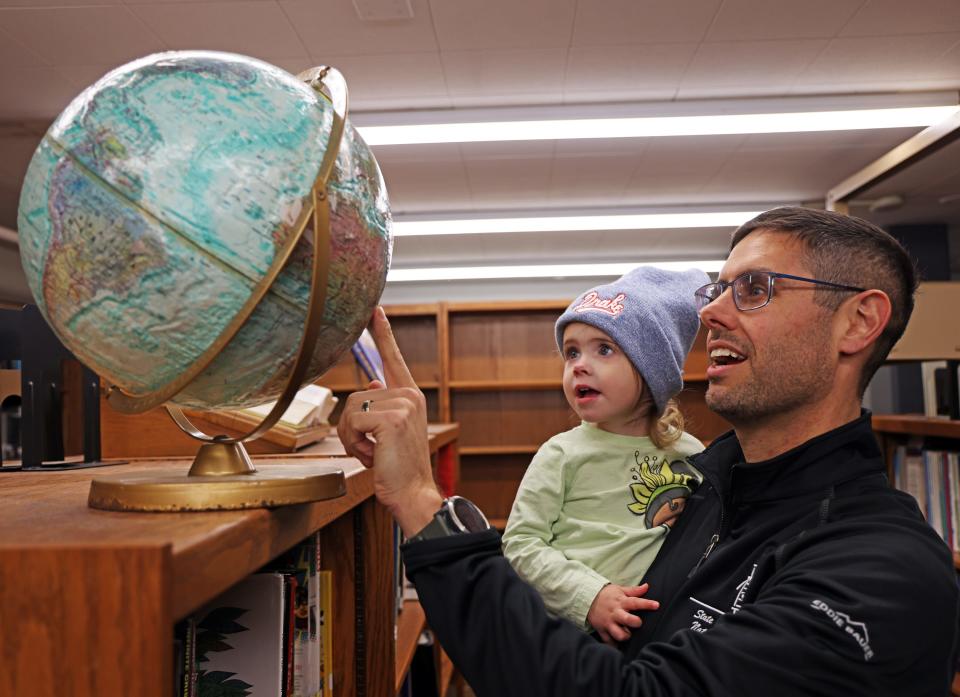 State Sen. Nate Boulton shows his daughter, Alys, 2, a globe before the event as Democrats gather in person on Iowa Caucus night in Polk County on Monday at the East High School library in Des Moines.