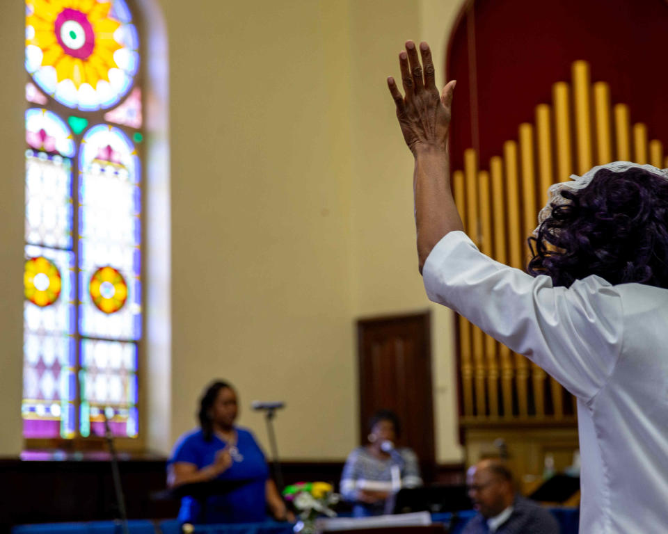 A women raising her hands while singing during worship at the New Bethel CME Church in Rochester, N.Y. on Aug. 6, 2023. 