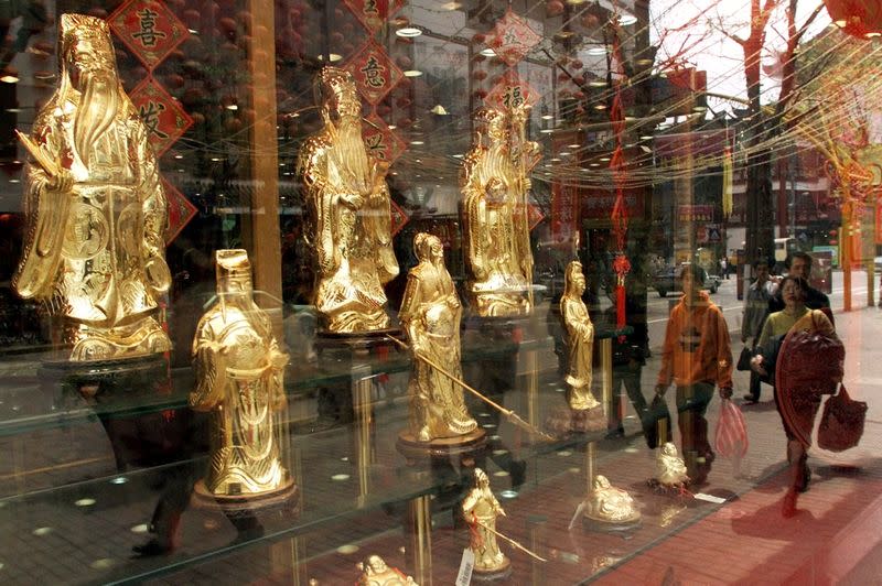 FILE PHOTO: CHINESE SHOPPERS WALK PAST A GOLD SHOP IN SHANGHAI.