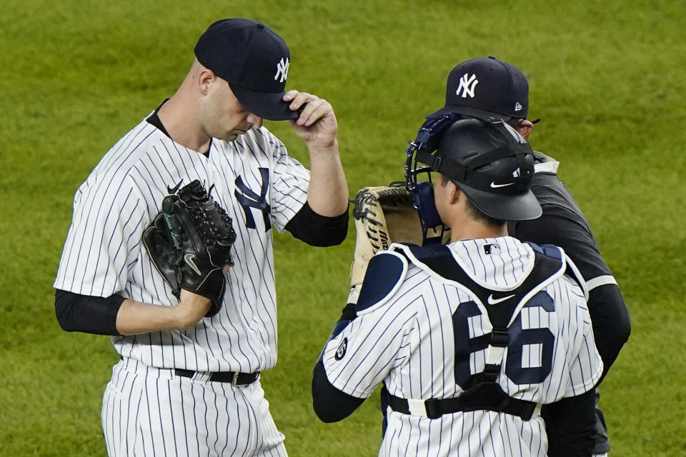 New York Yankees catcher Kyle Higashioka (66) and pitching coach Matt Blake, (behind the catcher) confer with Yankees relief pitcher Lucas Luetge, right, during a mound visit in the ninth inning of a baseball game against the Baltimore Orioles, Tuesday, April 6, 2021, at Yankee Stadium in New York. Luetge allowed a two-run, home run to Baltimore Orioles Rio Ruiz, but closed out the game in the Yankees 7-2 victory over Baltimore. (AP Photo/Kathy Willens)