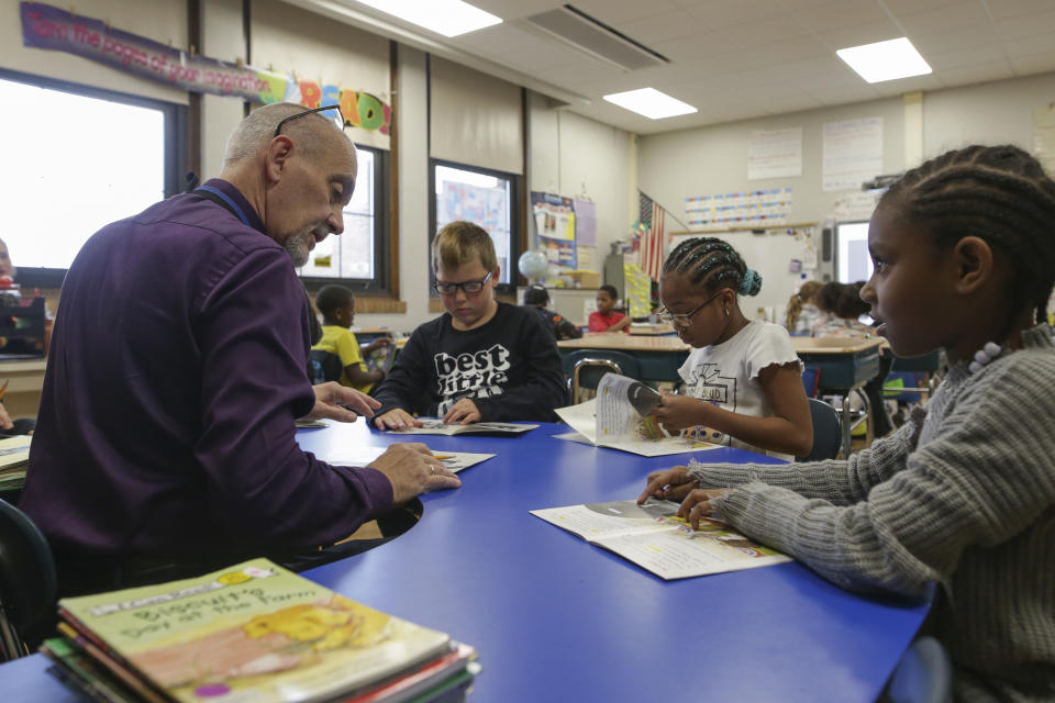 Richard Evans, a teacher at Hyde Park Elementary School, helps Shaundrea Baines, right, during a reading circle in class on Thursday, Oct. 20, 2022, in Niagara Falls, N.Y. (AP Photo/Joshua Bessex)