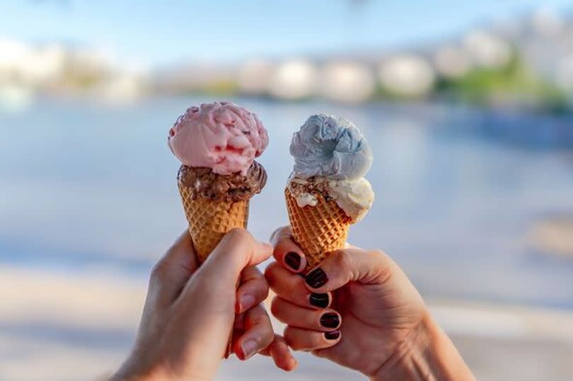 Woman and man hands holding colorful two ice cream waffle cone in hands on summer season, sea background