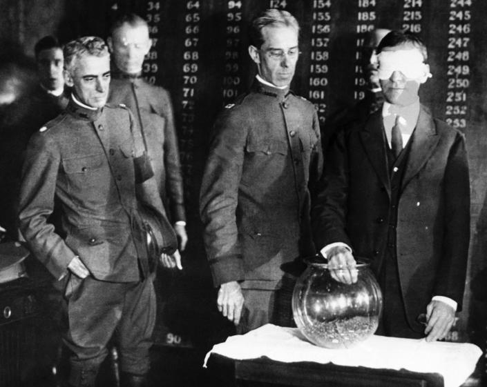 Secretary of war Henry Stimson will draw from this goldfish bowl on Oct. 29, 1917, the first number in a nationwide lottery to determine the order of calling men for military training under selective service. Secretary of war Newton D. Baker, right, in this scene from June 27, 1918, draws the first number in the world war 2nd draft.