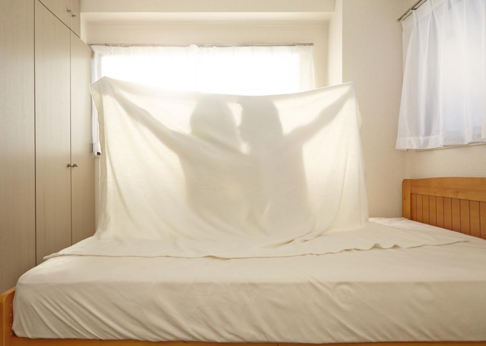 Couple in bed holding up sheet