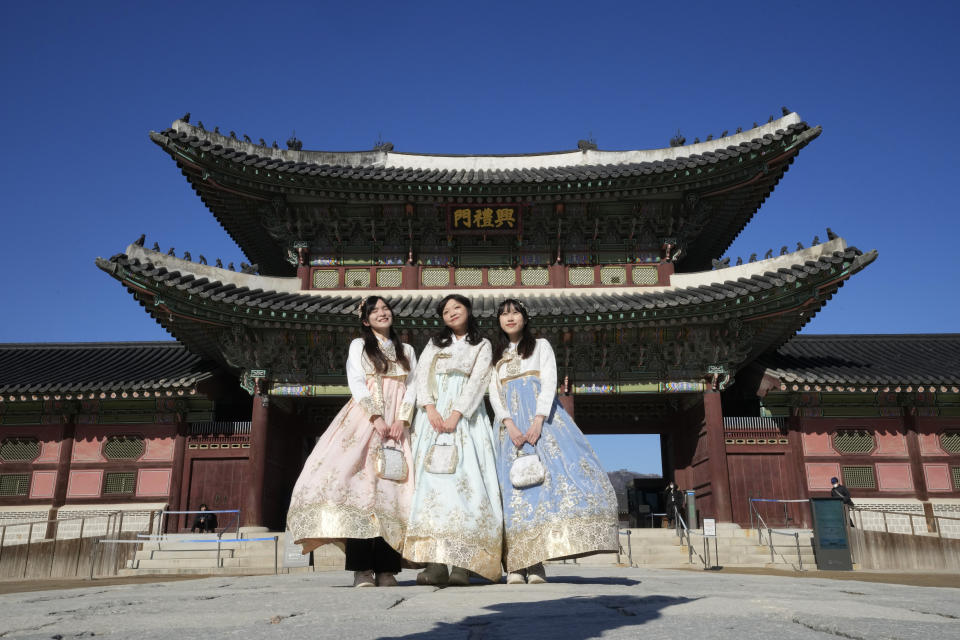 Hong Kong travelers wearing South Korean traditional "Hanbok" costume pose to take photos at the Gyeongbok Palace, the main royal palace during the Joseon Dynasty, and one of South Korea's well known landmarks in Seoul, South Korea on Jan. 16, 2023. The expected resumption of group tours from China is likely to bring far more visitors. (AP Photo/Ahn Young-joon)