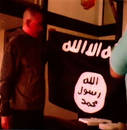 A photograph with a redacted date, and entered into federal court as an exhibit to support the government's motion to keep U.S. Army Sergeant Ikaika Erik Kang in detention without bond, shows what is described as Kang holding the Islamic State Flag after pledging allegiance to the Islamic State. Kang is charged with trying to provide material support to Islamic State extremists. the U.S. District Court for the District of Hawaii/Handout via REUTERS