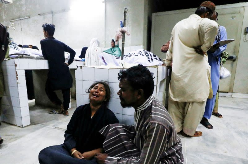 People mourn the death of a relative, who was killed along with others in a stampede during handout distribution, in Karachi