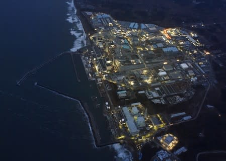 FILE PHOTO: Tokyo Electric Power Co.'s (TEPCO) tsunami-crippled Fukushima Daiichi nuclear power plant is illuminated for decommissioning operation in the dusk in Okuma town, Fukushima prefecture, Japan, in this aerial view photo taken by Kyodo