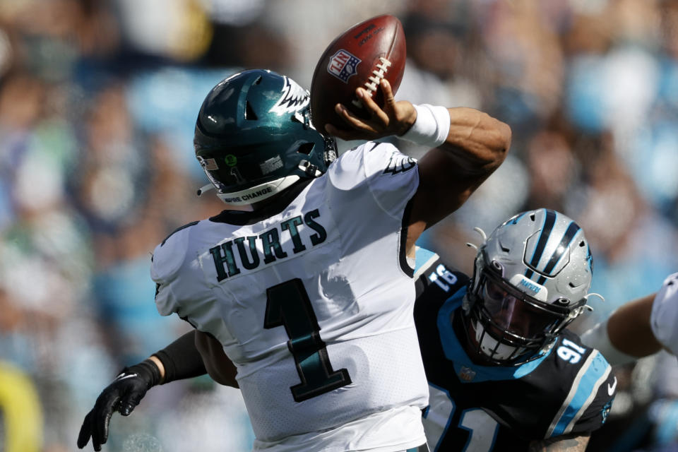 El quarterback Jalen Hurts (1) lanza un pase por los Eagles de Filadelfia bajo la presión del defensive end Morgan Fox, de los Panthers de Carolina, en partido de NFL el domingo 10 de octubre de 2021, en Charlotte, Carolina del Norte. (AP Foto/Nell Redmond)