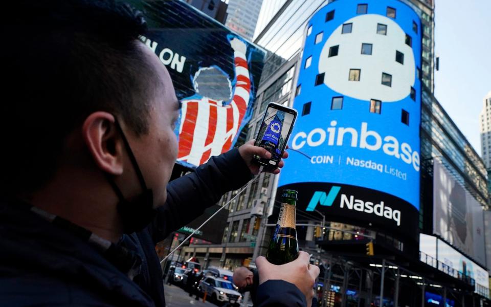 Coinbase employee Daniel Huynh holds a celebratory bottle of champagne outside the Nasdaq MarketSite on the day the digital currency exchange becoming a publicly traded company - Richard Drew/AP