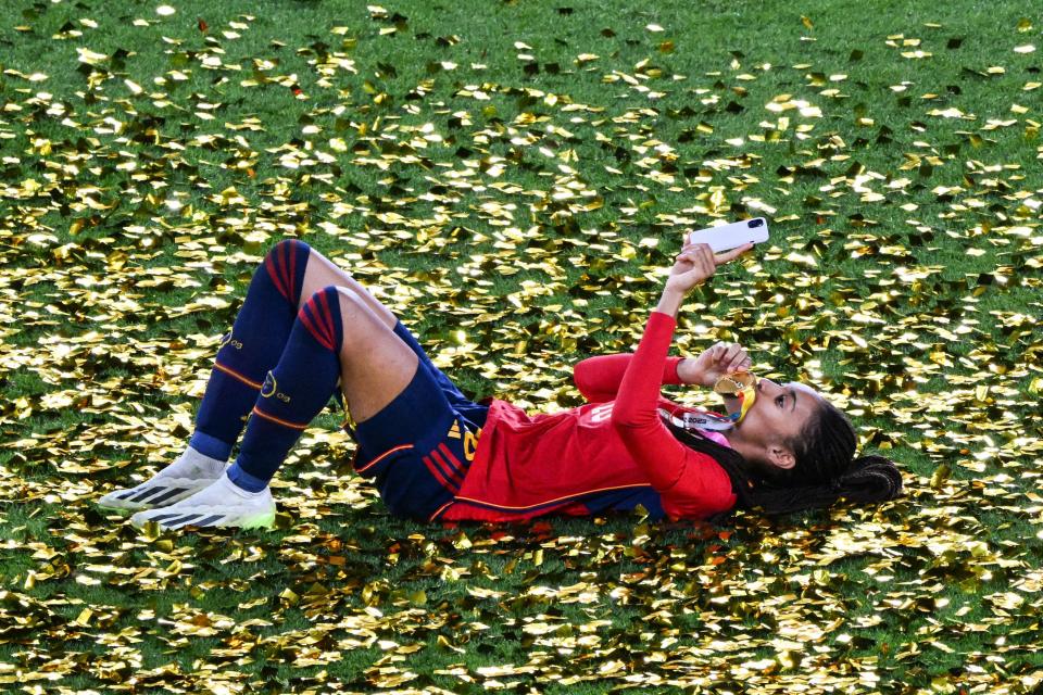 A member of Spain's women's national team takes a selfie as she lies on the ground and kisses her winner's medal