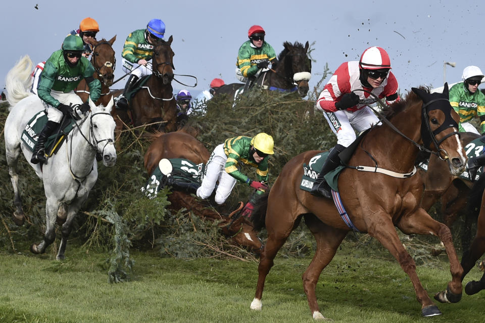 Jockey G. Sheehan riding Hogan's Height, center, falls down while trying to clear an obstacle during the Randox Grand National Handicap Chase on the third day of the Grand National Horse Racing meeting at Aintree racecourse, near Liverpool, England, Saturday April 10, 2021. (Peter Powell/Pool via AP)