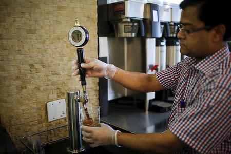 A Guy & Gallard cafeteria employee serves a nitrogen-infused cold brew coffee from Brooklyn-based roaster Gillies Coffee out of a tap at its cafeteria in New York July 31, 2015. REUTERS/Eduardo Munoz