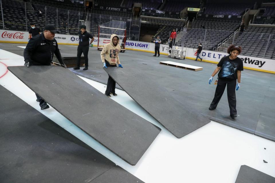 Employee at Crypto.com Arena removes rubber mats covering the ice.