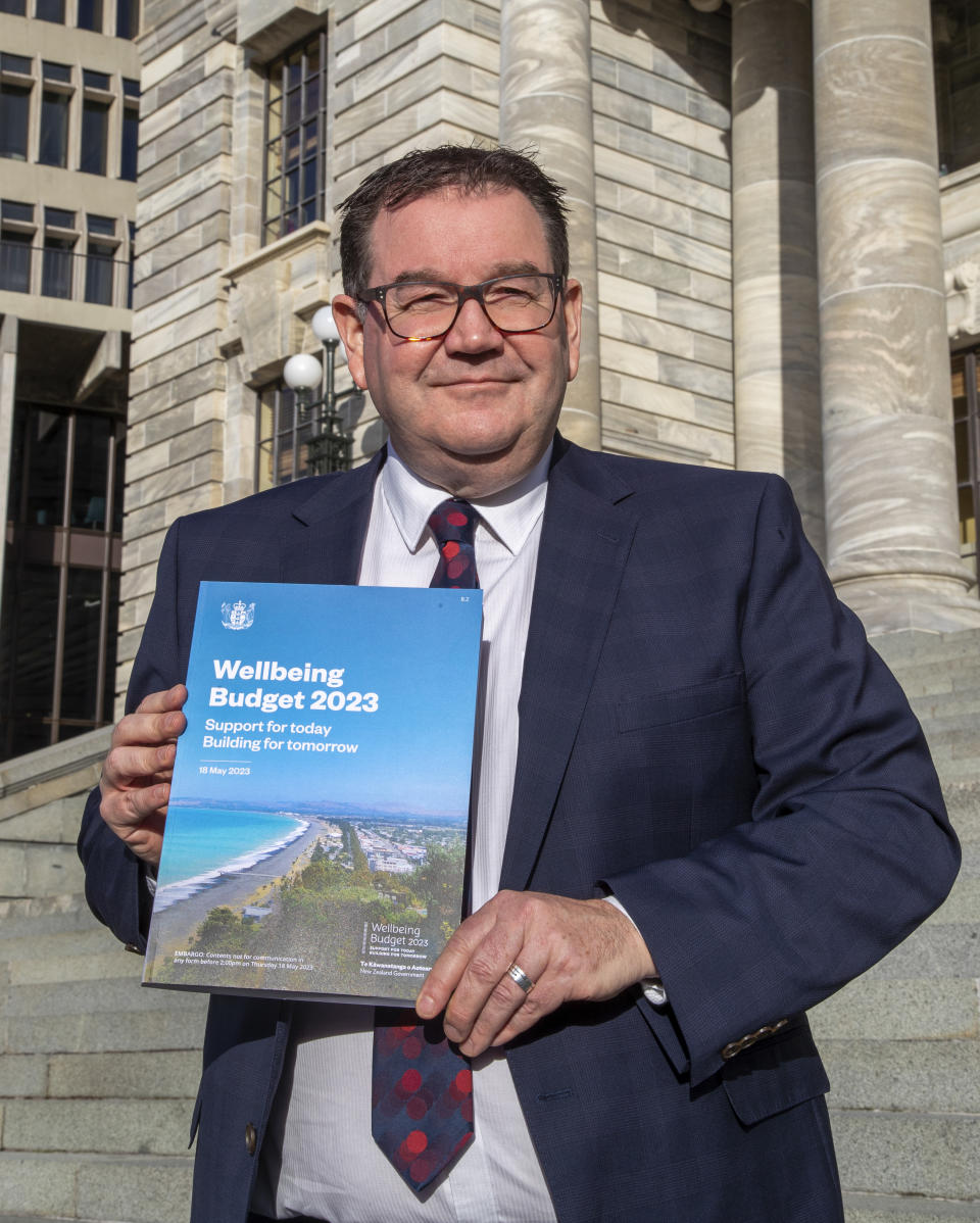 New Zealand Finance Minister Grant Robertson poses with the front cover of his Budget 2023 on the steps of Parliament in Wellington, New Zealand, Wednesday, May 17, 2023. New Zealand’s government on Thursday offered some modest financial relief to many people by making most prescription medicines free and increasing subsidies for childcare and public transportation. (Mark Mitchell/New Zealand Herald via AP)