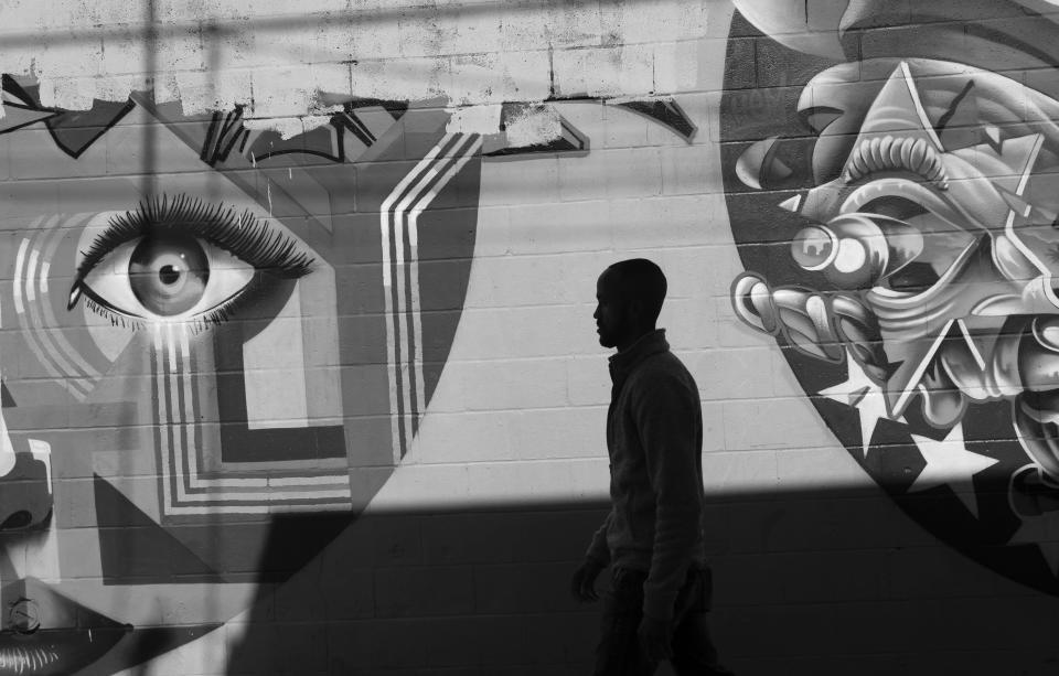 Jeffrey Rambo walks along the street in front of a mural in the Barrio Logan neighborhood of San Diego.
