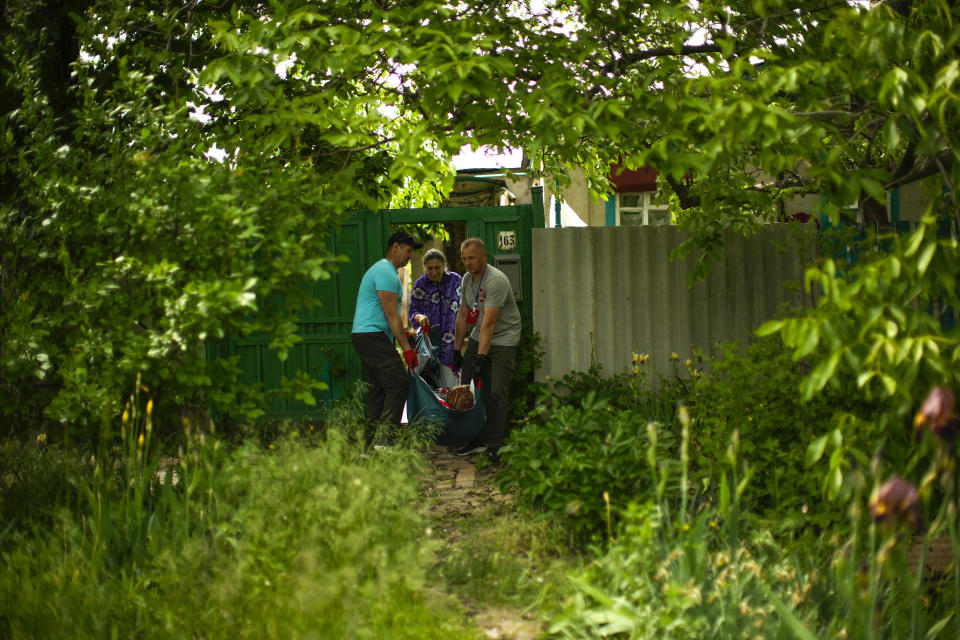 Roman Zhylenkov, right, and another volunteer of Vostok SOS charitable organisation carry an elderly woman from her home in an evacuation in Kramatorsk, eastern Ukraine, Thursday, May 26, 2022. Volunteer drivers are risking everything to deliver humanitarian aid to Ukrainians behind the front lines of the war — and to help many of them escape. The routes are dangerous and long and the drivers risk detention, injury or death. (AP Photo/Francisco Seco)