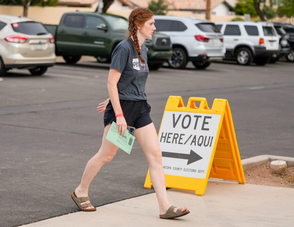 Chandler resident Amanda Lancaster walks into the voting center at the Chandler Unified School District Office with her ballot in hand on Aug. 2, 2022.