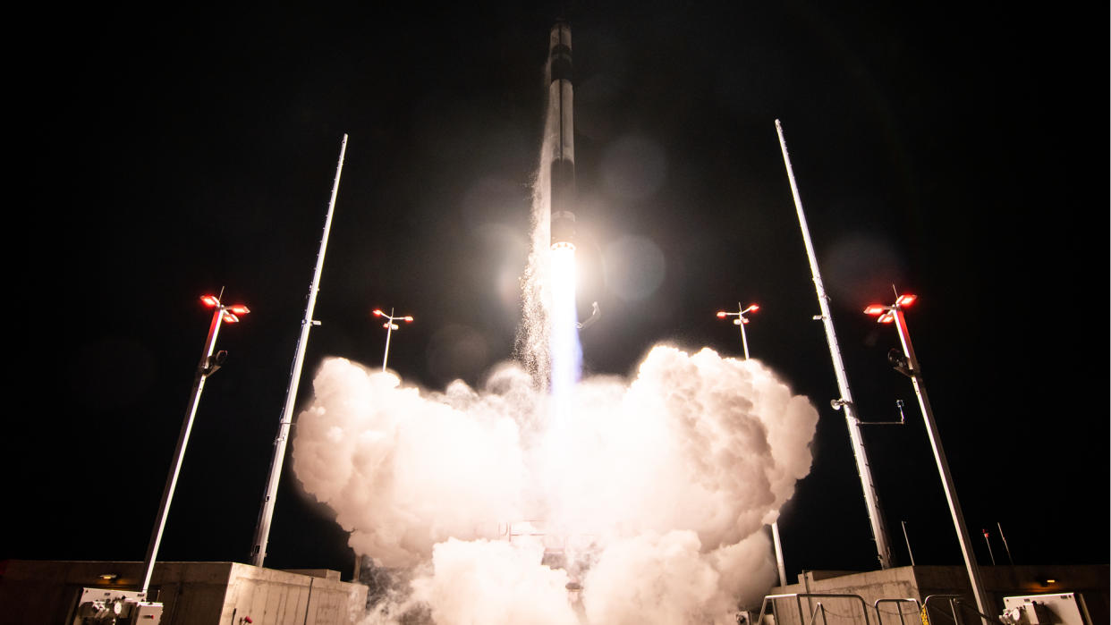  a black and white rocket lab electron rocket launches at night into a black sky 