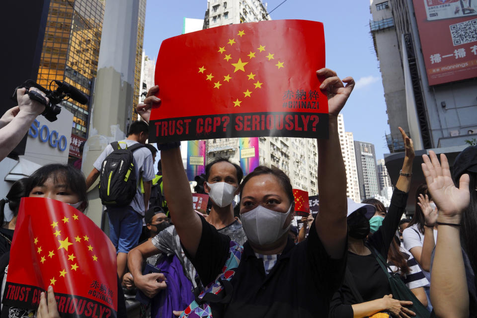 Protesters hold placards, chanting slogans during a rally on a street in Hong Kong, Sunday, Sept. 15, 2019. Thousands of Hong Kong people chanted slogans and marched Sunday at a downtown shopping district in defiance of a police ban, with shops shuttered amid fears of renewed violence in the months-long protests for democratic reforms in the semi-autonomous Chinese territory. (AP Photo/Vincent Yu)