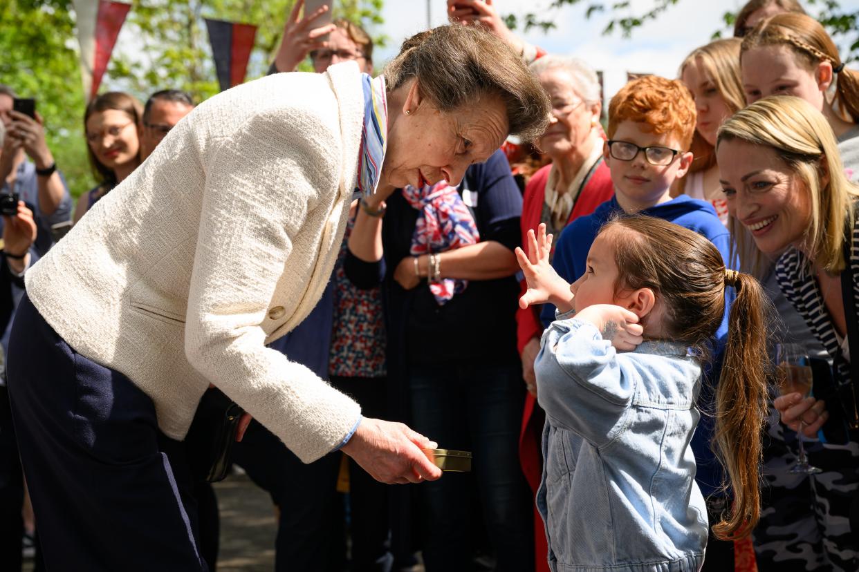 Anne presents a young girl with a commemorative tin of old coins (Getty)