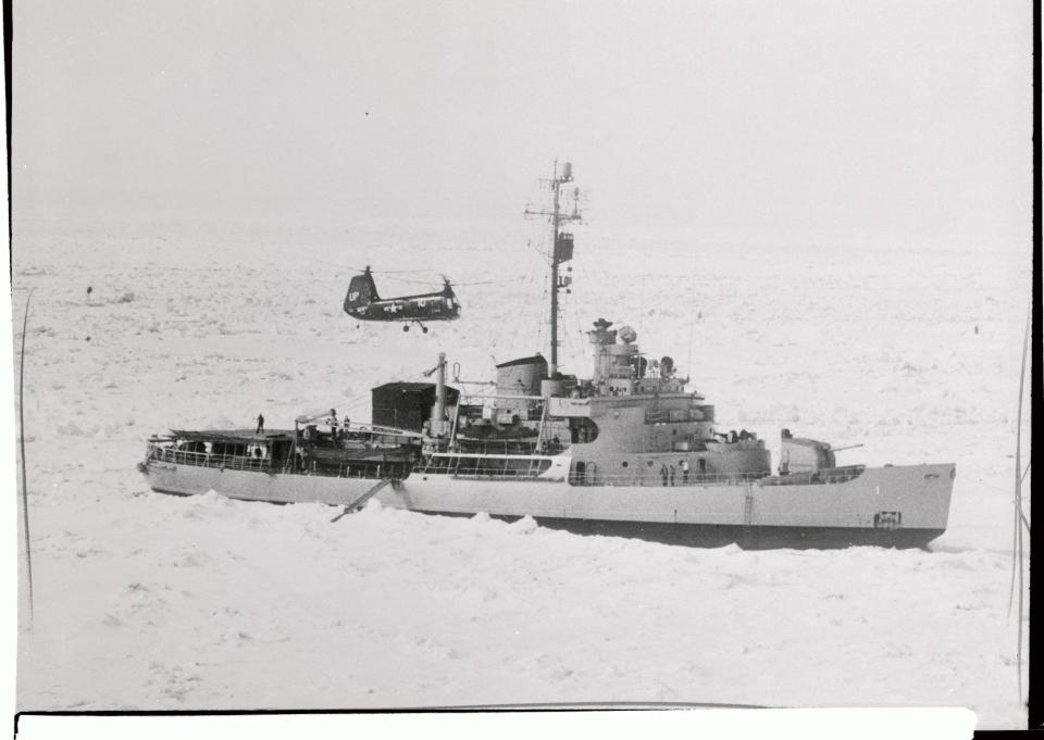 The US Navy icebreaker USS Burton Island is shown is Arctic waters as a helicopter prepares to land on its deck