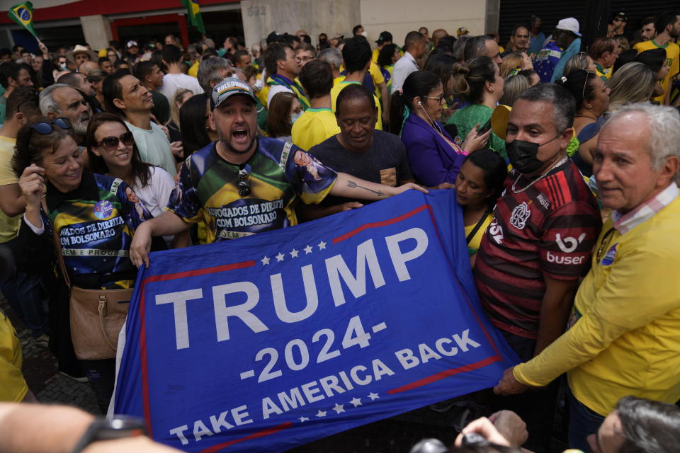Supporters of Brazilian President Jair Bolsonaro show a Trump campaign flag during a re-election campaign rally for Bolsonaro in Juiz de Fora, Minas Gerais state, Brazil, Tuesday, Aug. 16, 2022. Bolsonaro formally began his campaign for re-election in this town where he was stabbed during his 2018 campaign. General elections are set for Oct. 2. (AP Photo/Silvia Izquierdo)