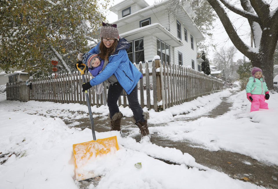 Stephanie Rytilahti shovels the sidewalk with her 1-year-old son, Orion, and 3-year-old daughter, Sorrel, at right, outside their East Side home during a snowfall in Madison, Wis., Thursday, Oct. 31, 2019. (Amber Arnold/Wisconsin State Journal via AP)