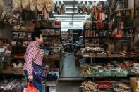 A woman walks past a shop on a street popular for dried foods used in traditional Chinese medicine and dishes in Hong Kong