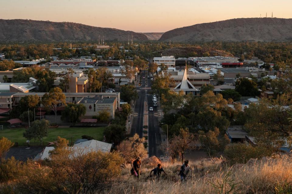 Local residents walk up a hill overlooking Alice Springs at sunset (Reuters)