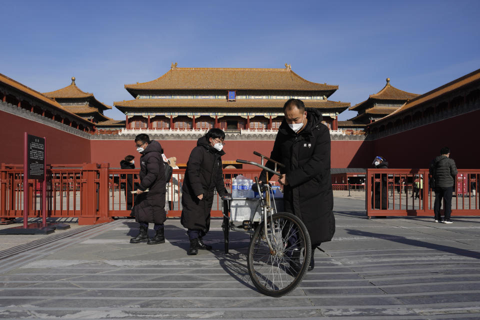 FILE - Workers wearing face masks push a tricycle delivering meals in front of the Forbidden City in Beijing on Dec. 14, 2022. Japanese Prime Minister Fumio Kishida announced Tuesday, Dec. 27, that Japan will tighten border controls against COVID-19 by requiring tests for all visitors from China starting Friday as a temporary emergency measure against the surging infections there. (AP Photo/Ng Han Guan, File)