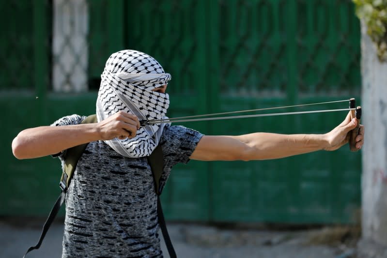 Palestinian demonstrator uses a slingshot to hurl stones at Israeli forces during an anti-Israel protest in al-Arroub refugee camp, in the Israeli-occupied West Bank