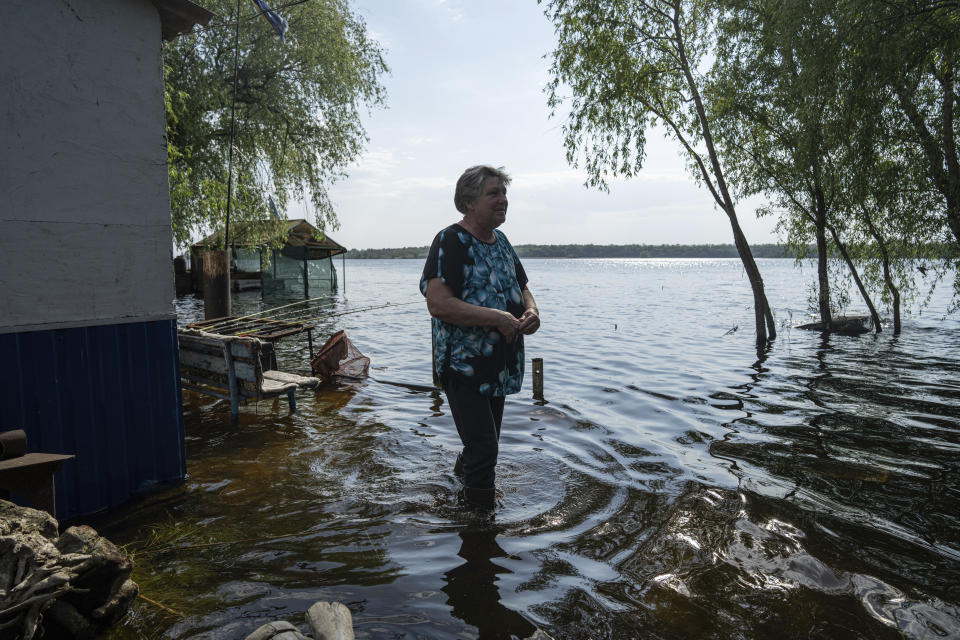 Lyudmila Kulachok, 54, right, stands at the flooded courtyard of her house in the island of Kakhovka reservoir on Dnipro river near Lysohirka, Ukraine, Thursday, May 18, 2023. Damage that has gone unrepaired for months at a Russian-occupied dam is causing dangerously high water levels along a reservoir in southern Ukraine. (AP Photo/Evgeniy Maloletka)