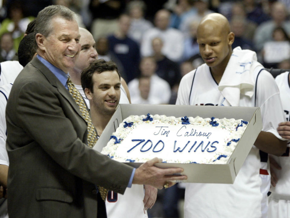 University of Connecticut basketball head coach Jim Calhoun (L) holds up a cake from his players after he achieved his 700th career win with an 83-64 win over Georgetown in Storrs, Connecticut March 2, 2005. With Calhoun are Sami Ameziane (C) and Chalie Villanueva. REUTERS/Brian Snyder BS