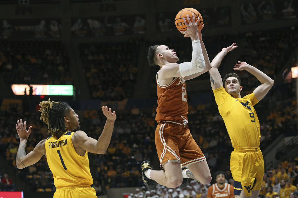 Texas guard Chendall Weaver (2) is defended by West Virginia guard Noah Farrakhan (1) and forward Ofri Naveh (9) during the first half of an NCAA college basketball game on Saturday, Jan. 13, 2024, in Morgantown, W.Va. (AP Photo/Kathleen Batten)