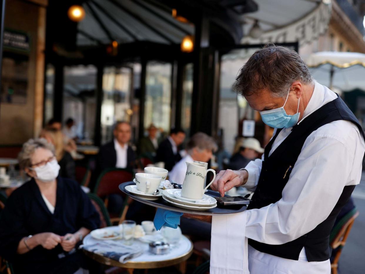 A waiter wearing a face mask serves at Cafe de Flore, as restaurants and cafes reopen following the covid-19 outbreak, in Paris, France, 2 June 2020: REUTERS