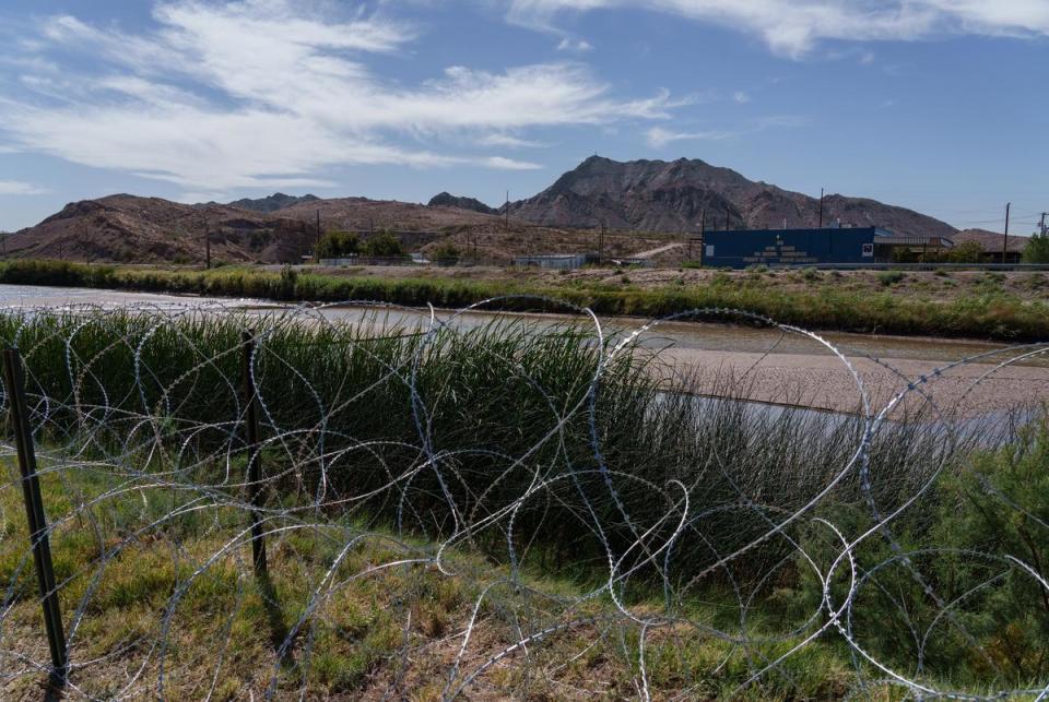 Mount Cristo Rey looms behind the Rio Grande where concertina wire is set up along the river bank, close to the Texas-New Mexico border in El Paso, Texas on Tuesday, October 17, 2023. Texas National Guard troops installed the concertina to prevent migrants who cross in New Mexico from entering Texas.