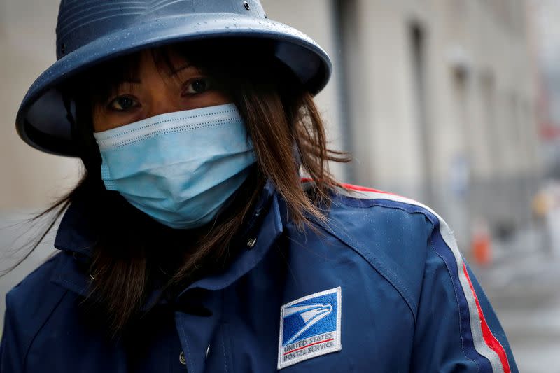 FILE PHOTO: A United States Postal Service (USPS) worker works in the rain in Manhattan during outbreak of coronavirus disease (COVID-19) in New York