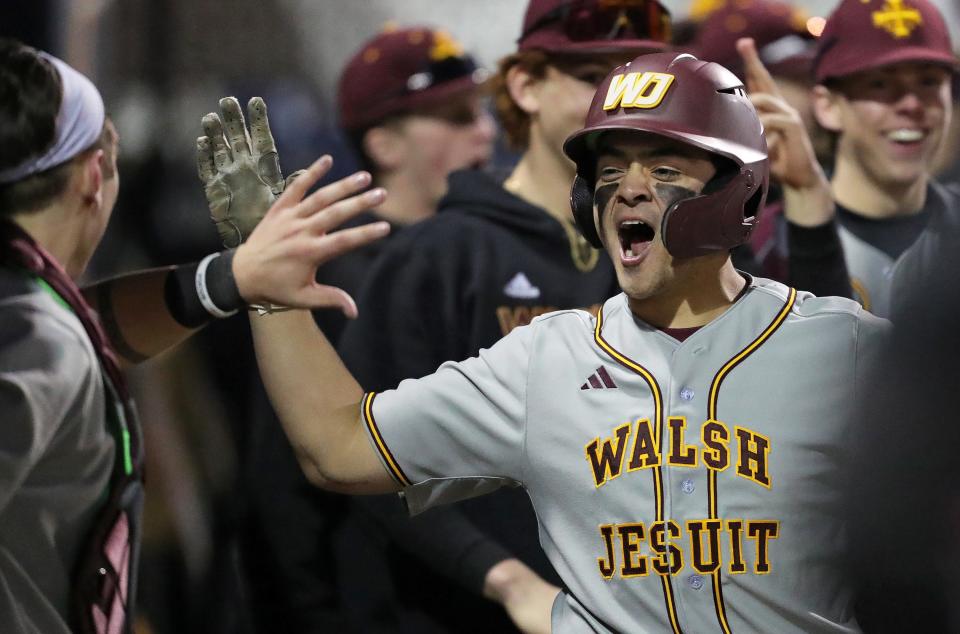 Walsh Jesuit designated hitter John Simecek celebrates with his teammates in the dugout after stealing home against STVM at Kent State University's Schoonover Stadium on April 6.