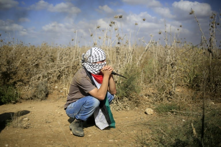 A Palestinian protester, holding a knife, looks on during clashes with Israeli security forces near the border fence between Israel and the Gaza Strip on October 9, 2015