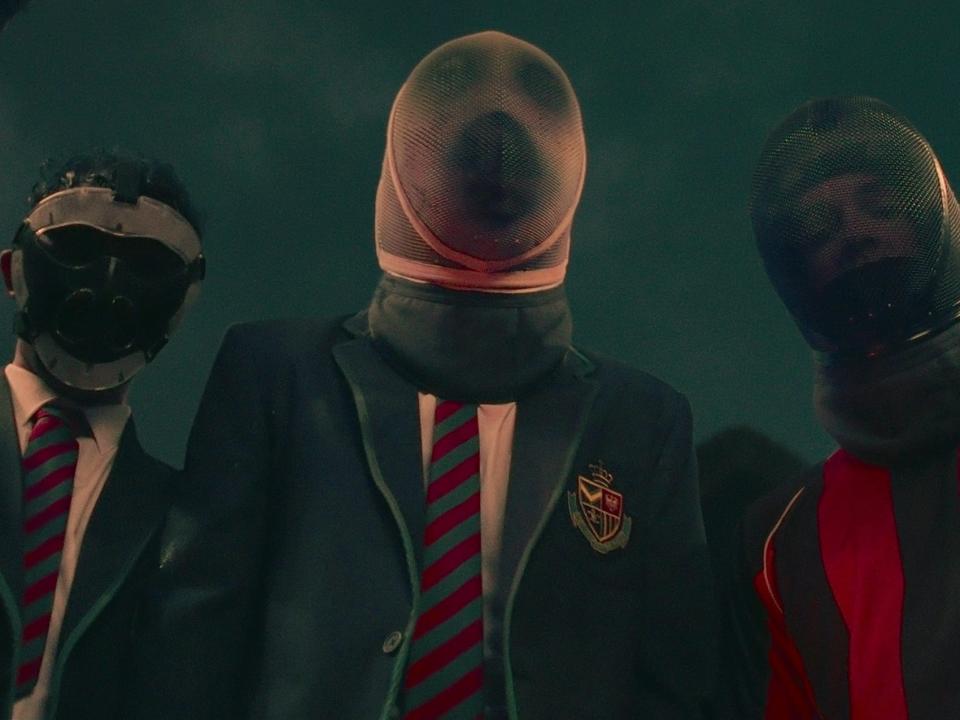 a group of people in school uniforms and football shirts wearing masks over their head
