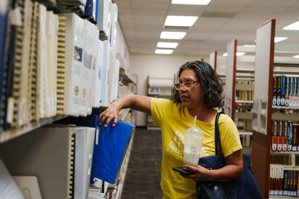 Linda Shosie takes a binder from the TCE Superfund Information Library section in the Valencia Public Library on July 15, 2022 in Tucson, AZ.