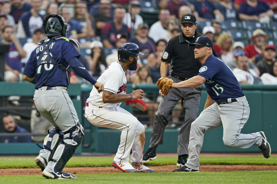 Seattle Mariners' Kyle Seager, right, tags out Cleveland Indians' Amed Rosario during the fourth inning of a baseball game Friday, June 11, 2021, in Cleveland. Catcher Jose Godoy, left, watches. (AP Photo/Tony Dejak)