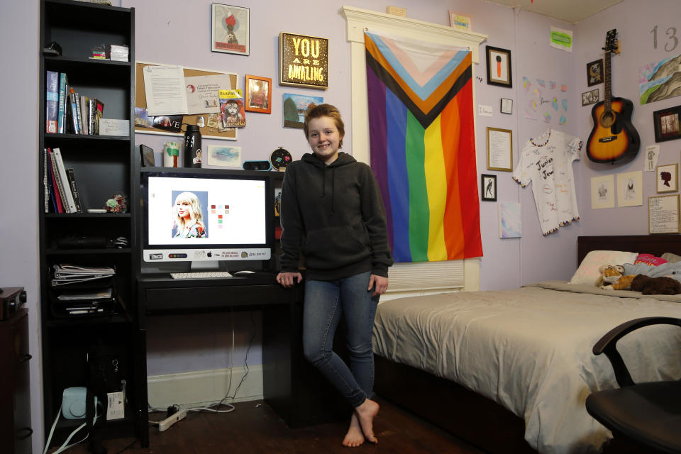 Graciela Leahy, 13, an eighth grader at Ohio's Columbus Gifted Academy, stands next to her computer in her bedroom, in Columbus, Ohio, Feb. 23, 2021, to begin a stretch of nearly six straight hours at her desk. A year later in the pandemic, the unplanned experiment with distance learning continues for thousands of students like Leahy who have yet to set foot back in classrooms. (AP Photo/Jay LaPrete)