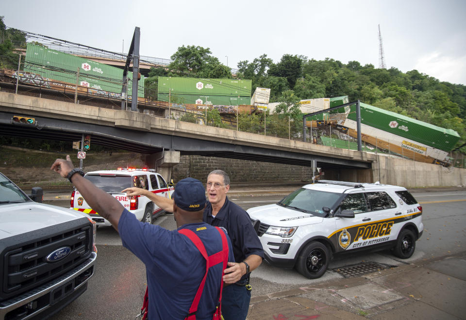 Emergency personnel work the scene of a train derailment above Carson Street on Sunday, Aug. 5, 2018, near Station Square in Pittsburgh. Four cars from a freight train derailed in Pittsburgh, sending containers tumbling down a hillside onto light rail tracks below, but no injuries have been reported, authorities said. (Steph Chambers/Pittsburgh Post-Gazette via AP)