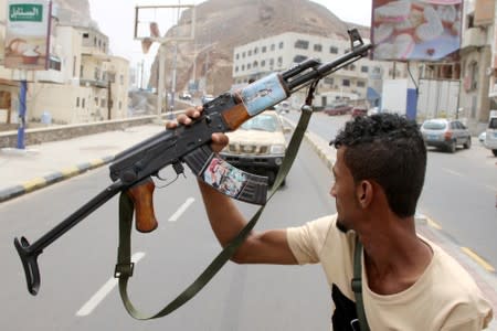 A member of Yemen's southern separatist holds his weapon with a picture of Muneer al-Yafee during a funeral of Brigadier General Muneer al-Yafee and his comrades killed in a Houthi missile attack, in Aden